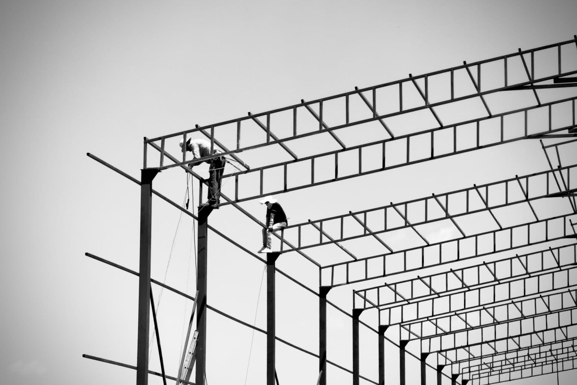 Ironworkers setting steel beams on a high-rise frame